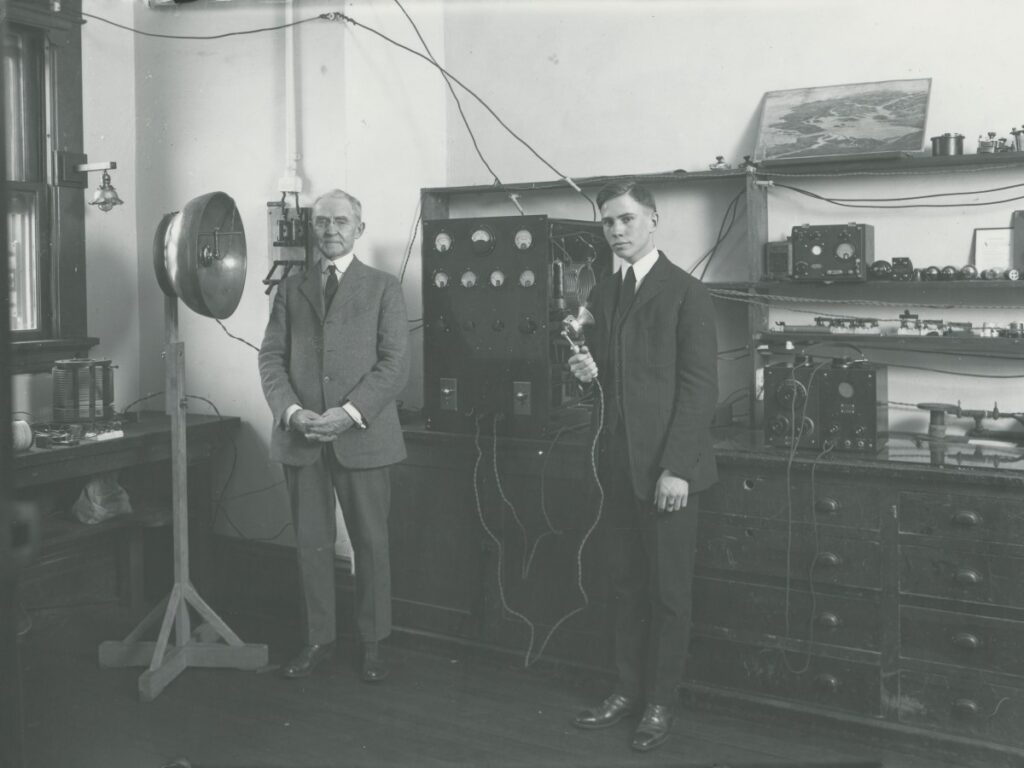 Pictured (left) with a student assistant in the University’s first radio lab (WPAK, 1924)