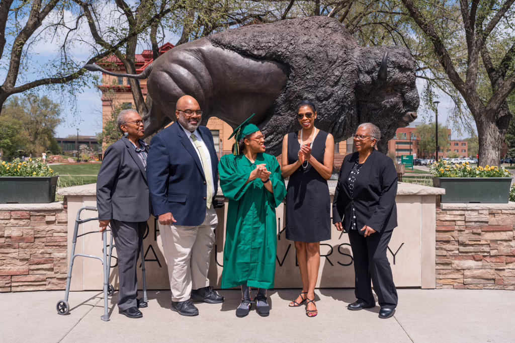 NDSU Transition and Access Program graduate Alexander Aikens standing in front of the bison statue with her family, including Dr. Shontarius Aikens and Christyal Alexington.
